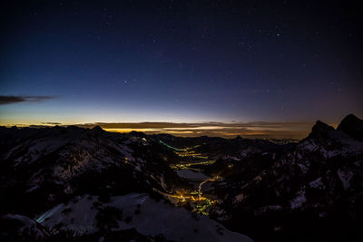 Scenic view of snowcapped mountains against sky at night