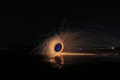 Light trails on beach against sky at night