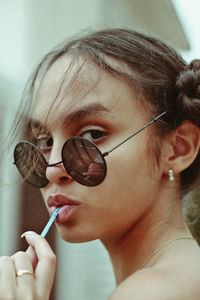 Close-up of woman wearing sunglasses eating lollipop