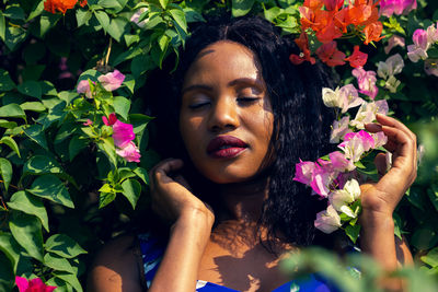 Content black woman smelling with flowers in park.