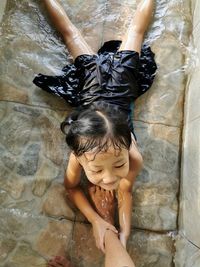 High angle view of mother and girl lying in water