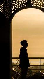 Rear view of silhouette man standing against sea