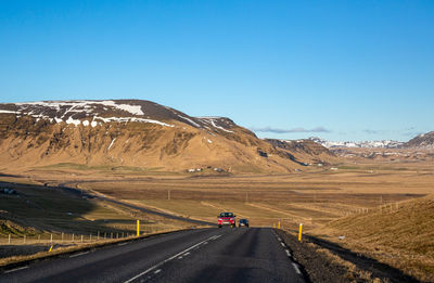 Road leading towards mountain against clear sky