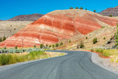 Road leading towards mountain against clear sky