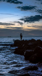 Silhouette of man fishing in sea