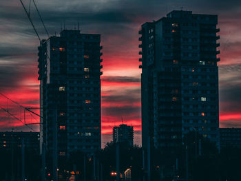 Illuminated buildings in city against sky at sunset