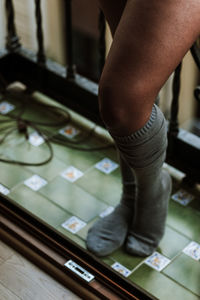 From above of crop unrecognizable ethnic female in cozy knee socks standing on balcony while resting at home