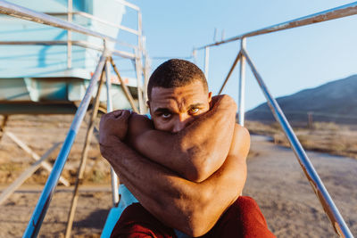 Portrait of male with piercing eyes and arms wrapped around his face