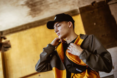 Young man looking away while standing against wall