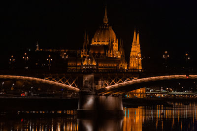 Illuminated bridge over river in city at night