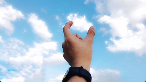 Close-up of hand gesturing against sky