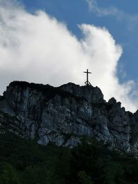 Low angle view of cross on rock against sky