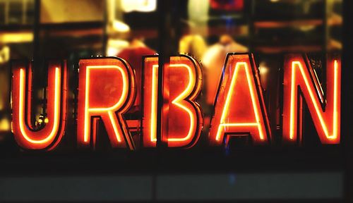 Close-up of illuminated neon lights text seen through glass window