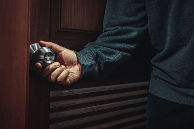 Midsection of man holding wood at home