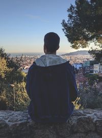 Rear view of man looking at city against sky