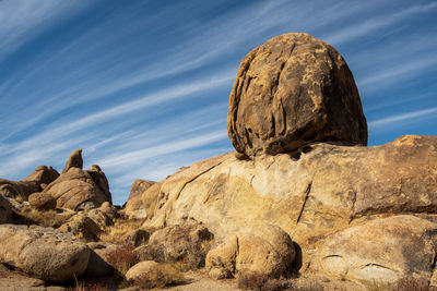 Rock formation on desert land against blue sky with layered clouds