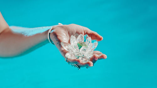 Low section of woman holding water against blue background