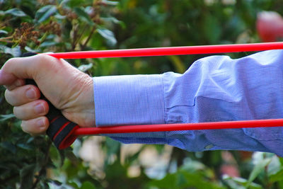 Cropped hand of man holding resistance band outdoors