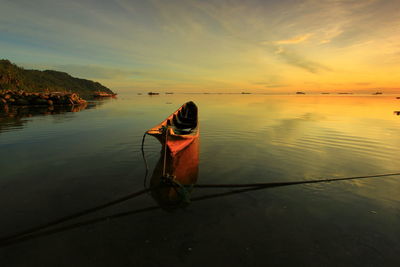 Man in boat on sea against sky during sunset