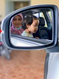 Portrait of a girl with reflection on side-view mirror