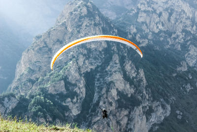 Person paragliding against mountains