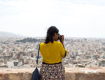 Rear view of young woman photographing cityscape