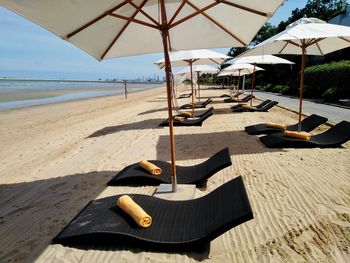 Deck chairs on sand at beach against sky