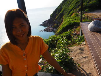 Portrait of smiling young woman by sea