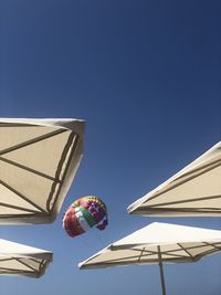 Low angle view of parasol against clear blue sky