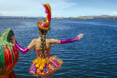 Rear view of woman with arms raised in sea