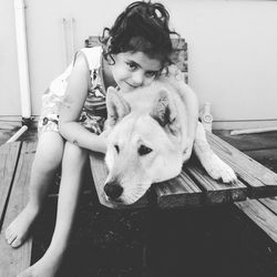 Portrait of girl embracing wolf dog while sitting on bench