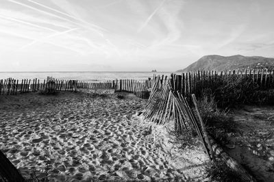 Wooden posts on beach against sky