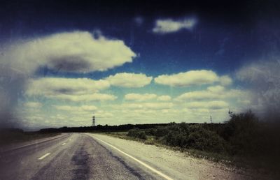 Surface level of country road against cloudy sky