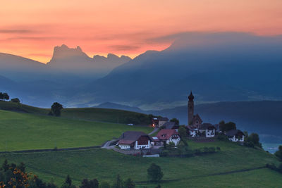 Scenic view of field by mountains against sky during sunset