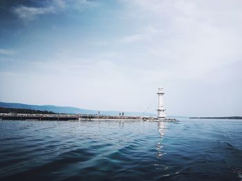 Lighthouse by sea against sky