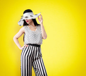 Portrait of woman wearing hat against yellow background