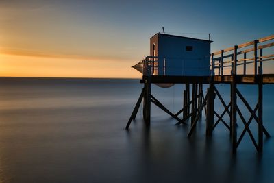 Pier over sea against sky during sunset