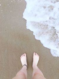 Low section of woman standing on shore at beach