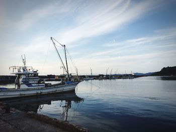 Boats moored at harbor against sky