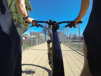 Man riding bicycle on footpath against clear blue sky