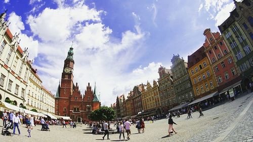 Panoramic view of people in town square against cloudy sky