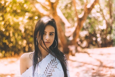 Portrait of young woman standing against tree