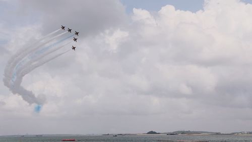 Low angle view of airplane flying over sea against sky