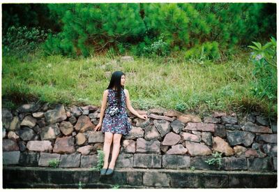 Full length of woman standing on stone wall