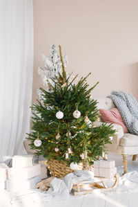 Christmas tree with toys on it in a wicker basket is on the floor in the living room