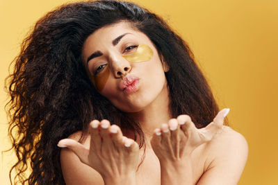 Portrait of young woman against yellow background