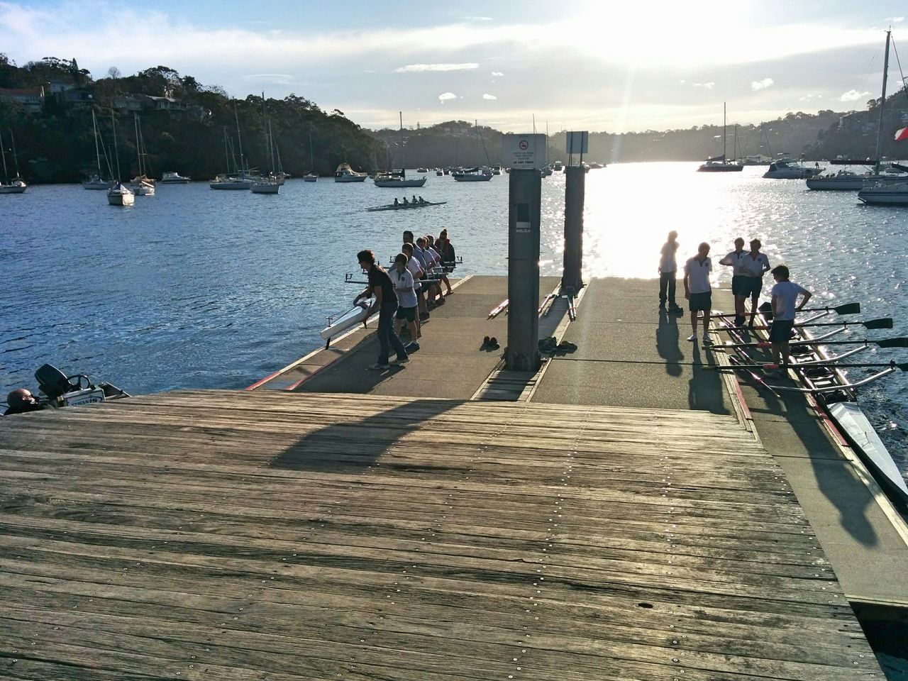 water, transportation, lifestyles, sky, leisure activity, men, sea, sunlight, nautical vessel, mode of transport, person, medium group of people, pier, large group of people, mountain, travel, tourist, cloud - sky, nature