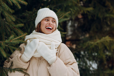 Portrait of young woman standing against trees