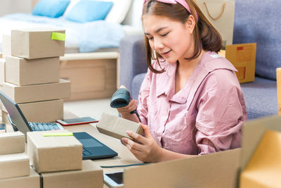 Woman scanning cardboard box with bar code reader at home