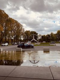 Wet street by trees against sky